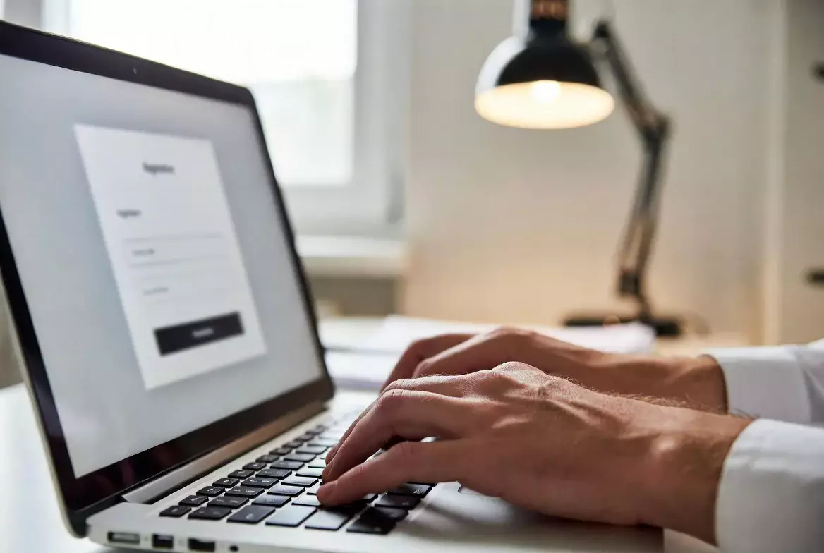 Hand tippt auf Laptop-Tastatur bei Online-Registrierung