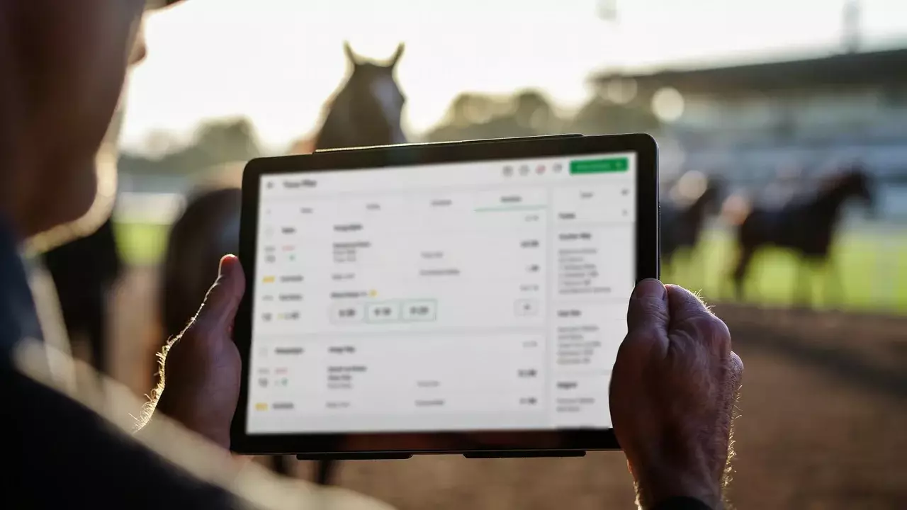 Person nutzt Tablet mit Pferdewetten-App am Renntag