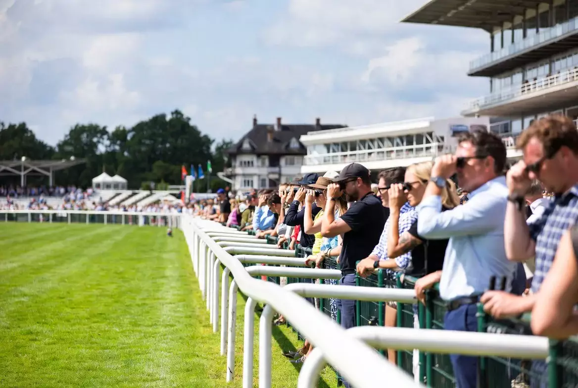 Zuschauer an der Rennbahn beobachten gespannt ein Pferderennen